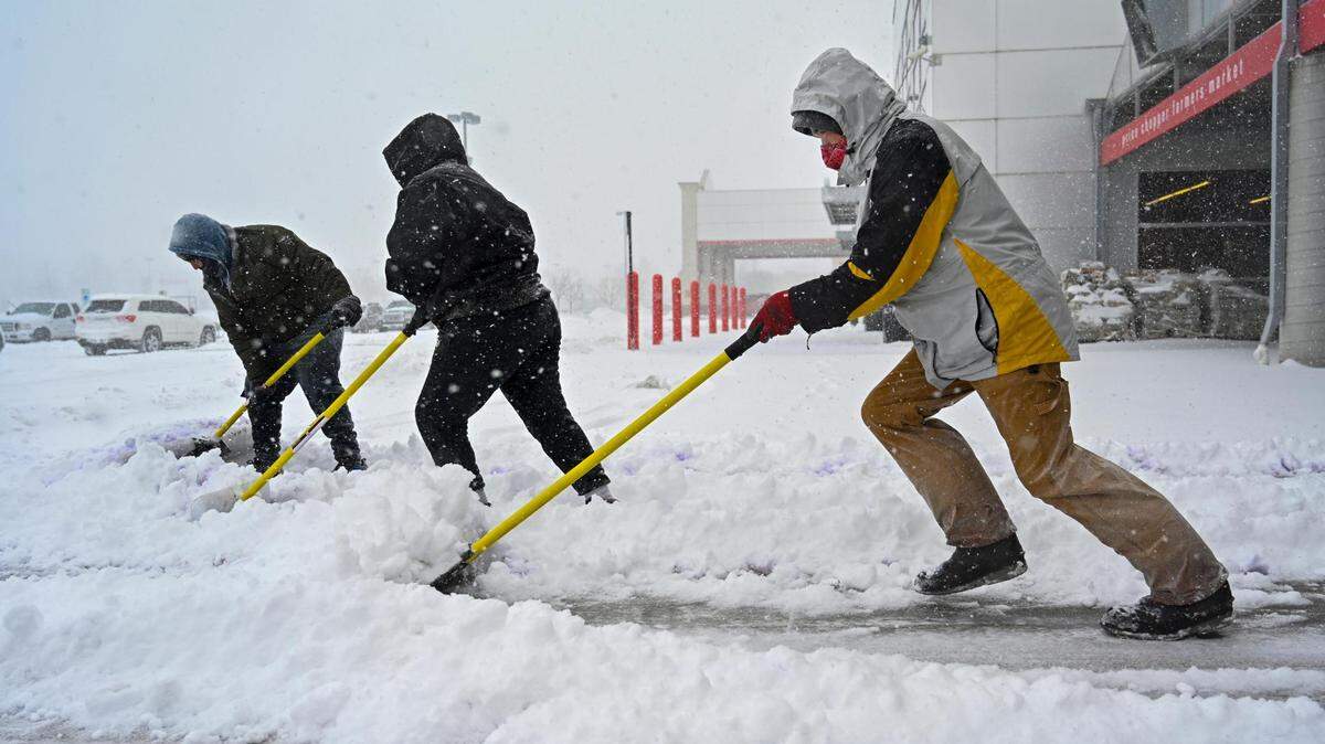 Workers from Impact Landscape of Kansas City, Kansas, braved the snowstorm to shovel the snow from the sidewalks at a grocery store on Thursday, Feb. 17, 2022, in Roeland Park.