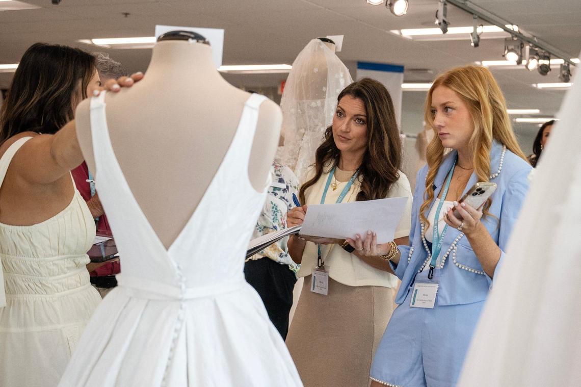Melissa Estess, center, of The Bridal Boutique by MeaMe, jots down notes as she observes a bridal dress on Monday, Aug. 5, 2024, in Lenexa.
