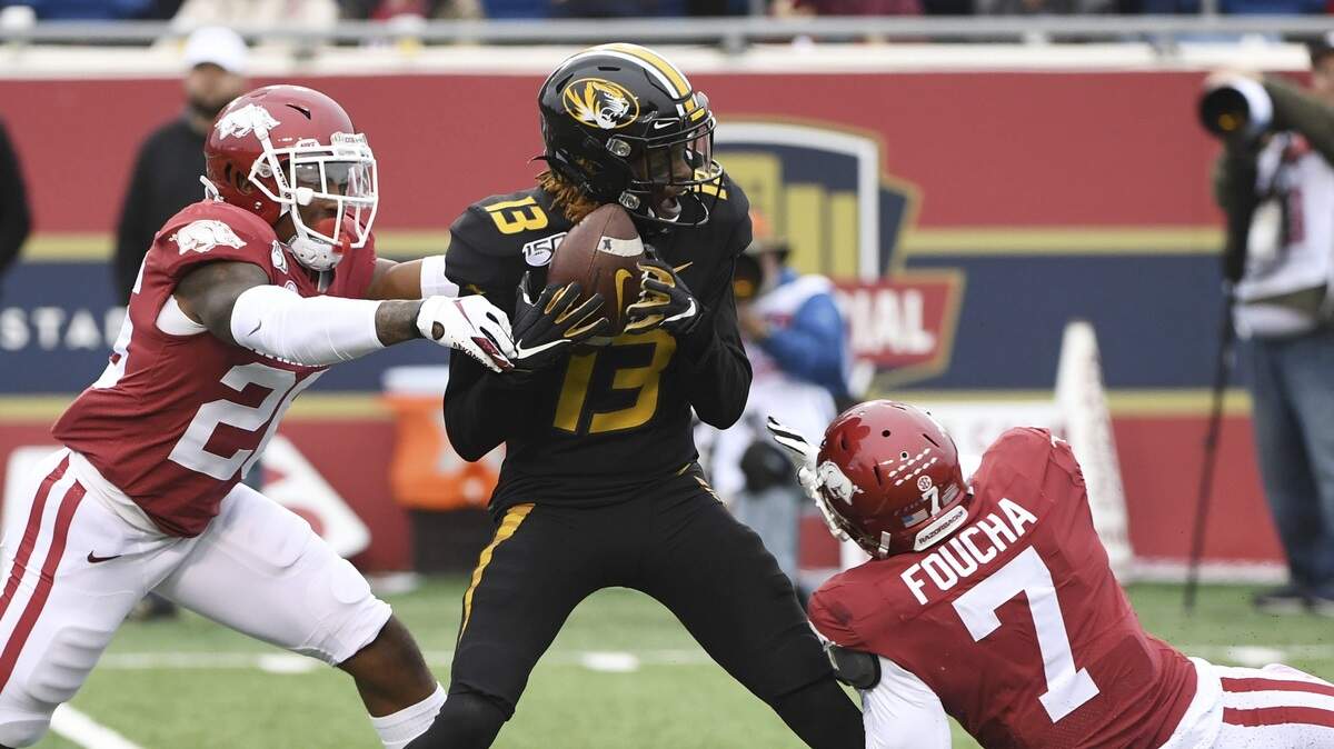 Missouri Tigers receiver Kam Scott makes a catch between Arkansas defenders Friday in Little Rock, Ark.