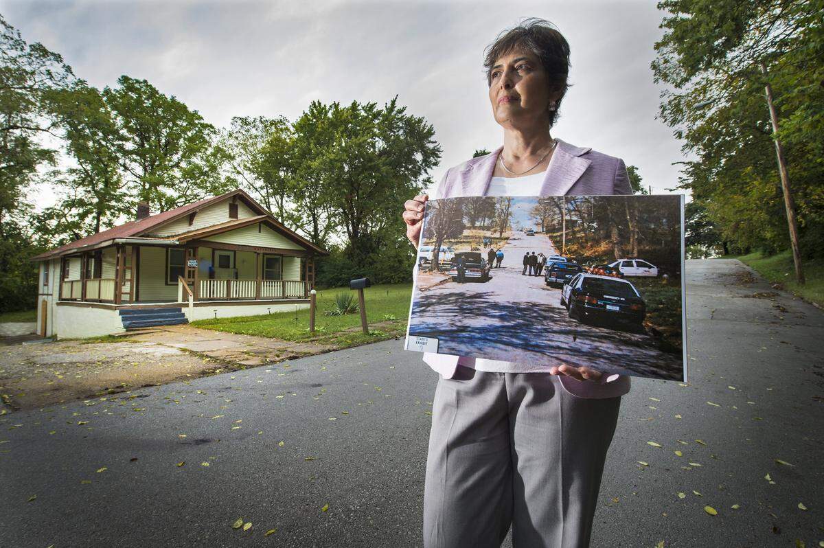 At the scene of a 1994 double-homicide, Cheryl Pilate, a lawyer, holds a police evidence photo taken shortly after the crime occurred in the 3000 block of Hutchings Street in Kansas City, Kan., on April 15, 1994. Pilate has been working for 7 years to get Lamonte McIntyre, who was convicted of the murders, exonerated. After uncovering new evidence and corruption in the case, Pilate has filed a motion with the courts to get his conviction set aside. McIntyre, 40, has been incarcerated since he was 18-years-old.