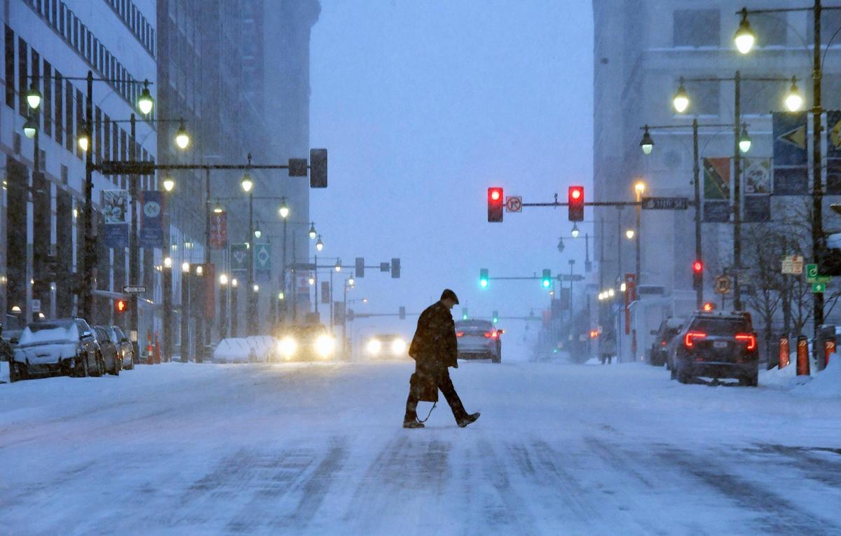 Snow continued to fall Wednesday morning over downtown Kansas City and the area as a major winter storm made its way across the plains states and an undeterred pedestrian made his way across Grand Blvd., near 11th Street. Forecasters called for up to a foot of snow with heavier amounts south of the metro area. Temperatures will dip below zero on Thursday night.