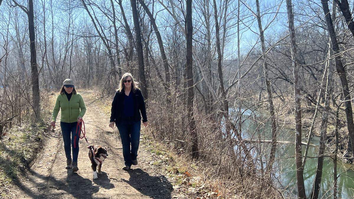 Johnson County Commissioners Charlotte O’Hara, left, and Becky Fast walk along the Blue River on the site of the old Kuhlman Diecasting factory. They want the county to take over the land and turn it into a park.
