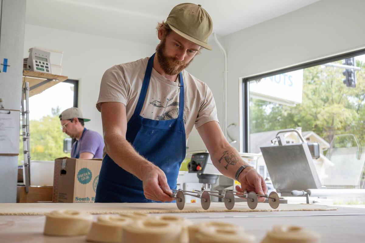 1900 Barker owner Taylor Petrehn measures and cuts dough to prepare ham and cheese croissants. He does the prep at his other Lawrence business, Taylor’s Donuts.