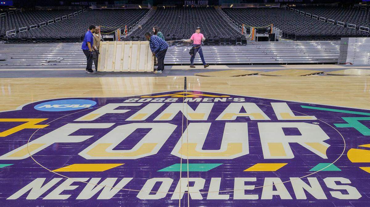 Workers install the court for the 2022 men’s Final Four NCAA college basketball tournament at the Superdome in New Orleans.