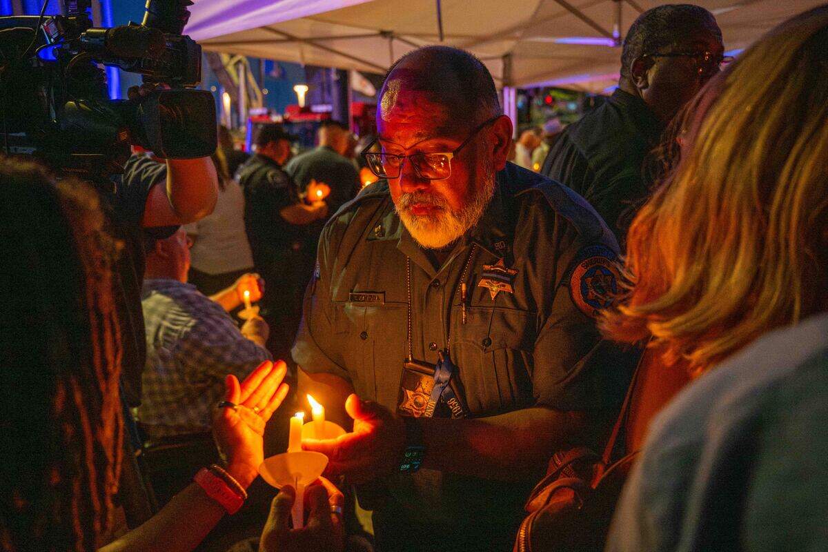 An officer of the Wyandotte County Sheriff’s department passes his flame to someone during a candlelight vigil held for slain KCK sheriff’s deputy Elijah Ming.