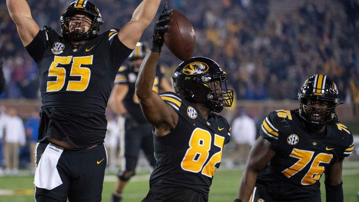 Missouri tight end Daniel Parker Jr., center, holds up the ball as teammates Michael Maietti, left, and Javon Foster, right, celebrate his winning catch during overtime of an NCAA college football game against Florida, Saturday, Nov. 20, 2021, in Columbia, Mo. (AP Photo/L.G. Patterson)