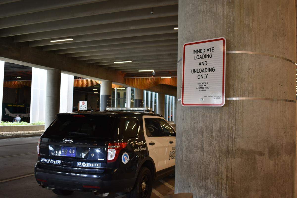 An airport police car is seen on Oct. 4, next to a sign instructing drivers not to stop in KCI’s arrivals lanes unless they are actively picking up passengers.