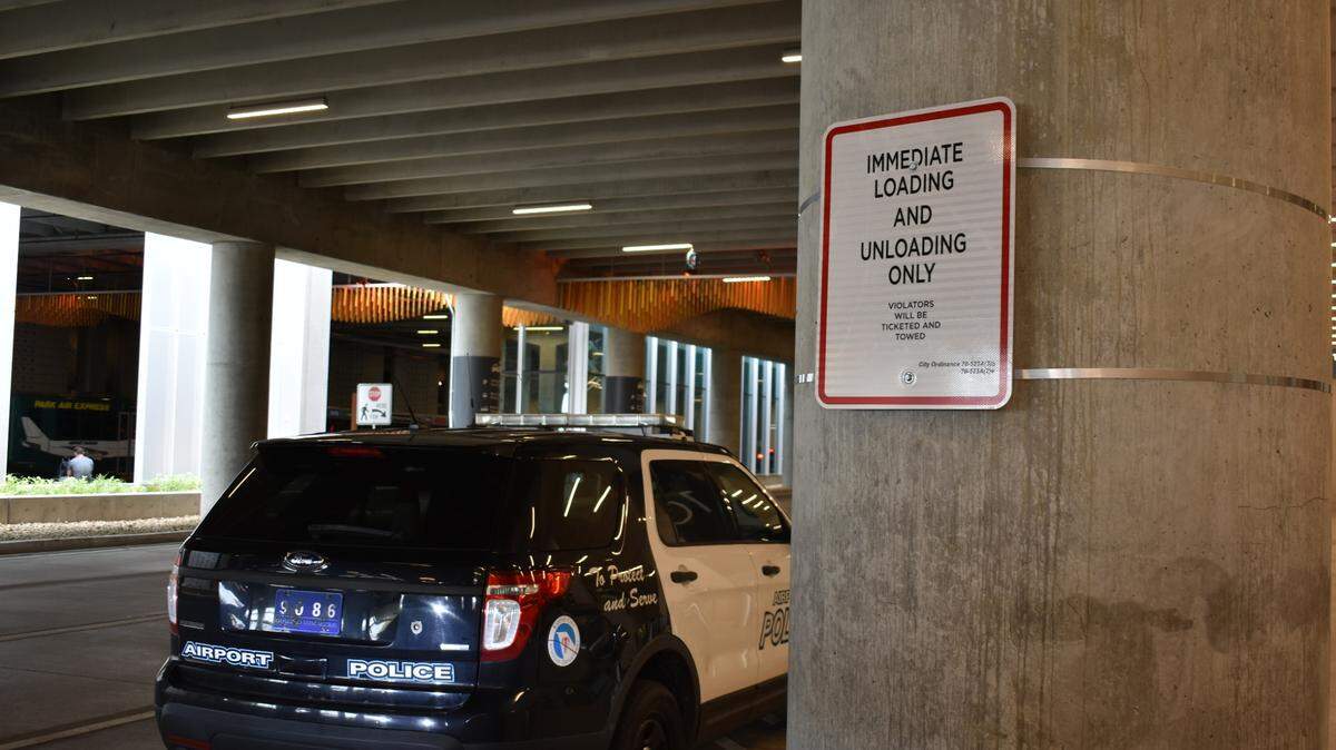 An airport police car is seen next to a sign instructing drivers not to stop in KCI’s arrivals lanes unless they are actively picking up passengers on Oct. 4, 2023.