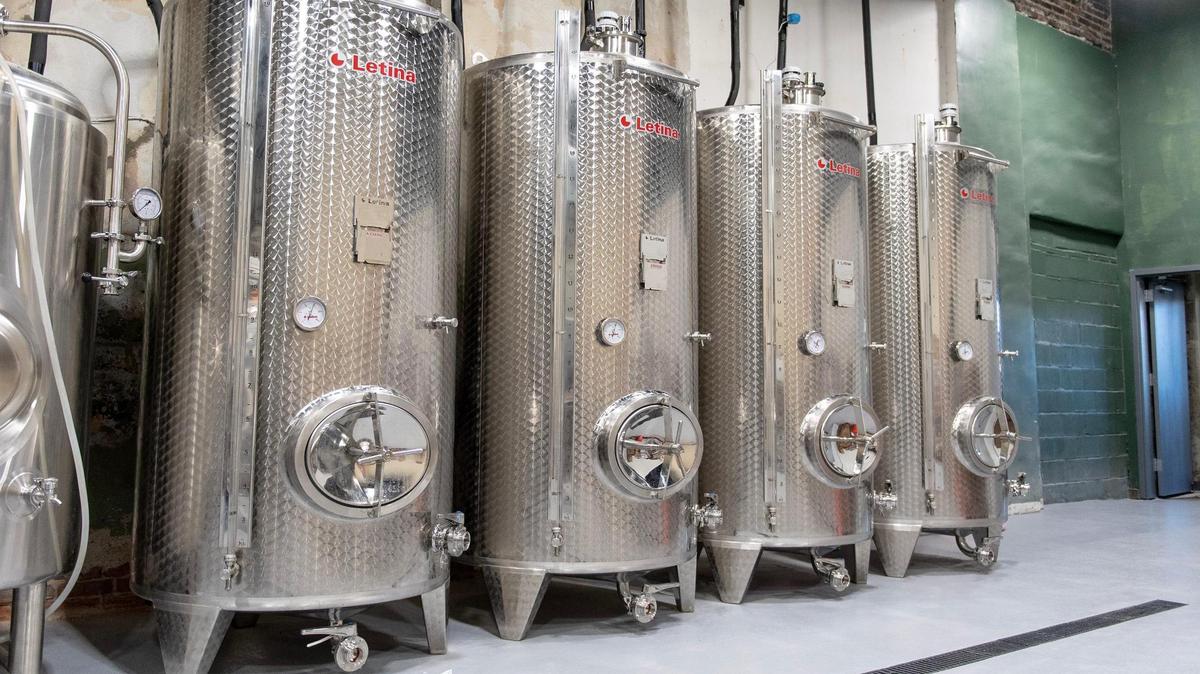 Four cider fermenters line a wall in the production room at Brick River Cider.