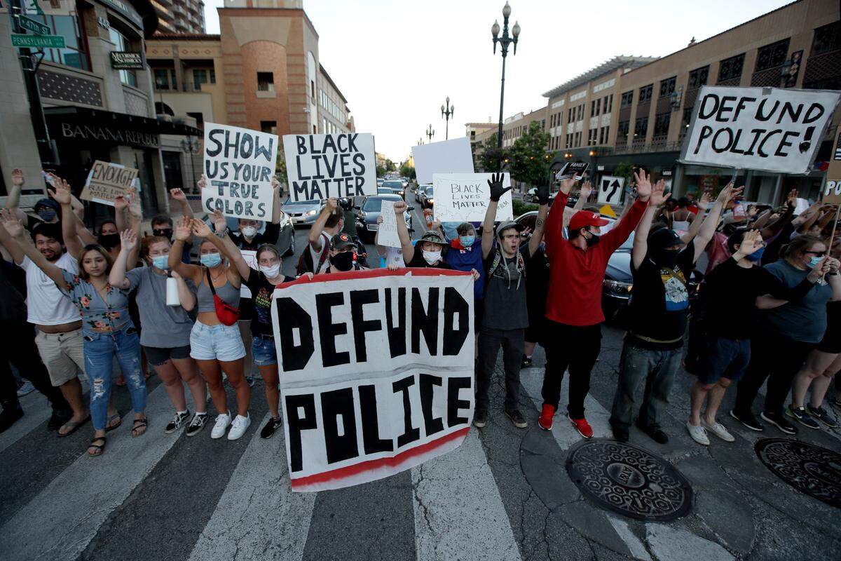 Demonstrators hold signs in the Country Club Plaza district of Kansas City, Mo. Saturday, June 13, 2020, as they protest the murder George Floyd by a Minneapolis police officer. (AP Photo/Charlie Riedel)