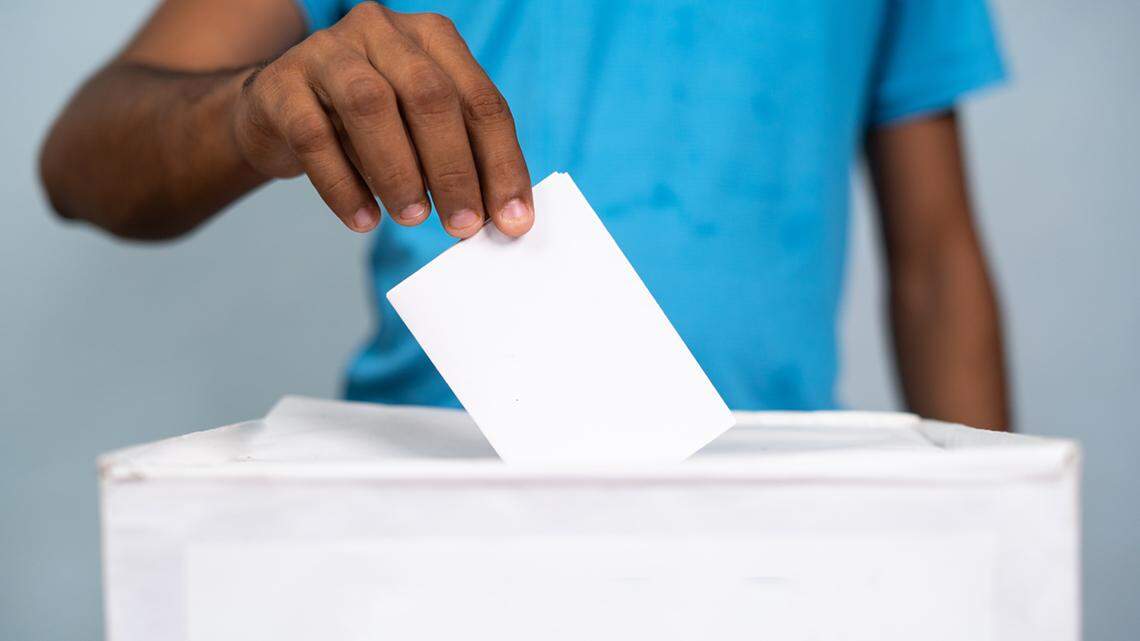 Man placing ballot paper into 2022 ballot box - concept of 2022 election. voting and democracy vote cast