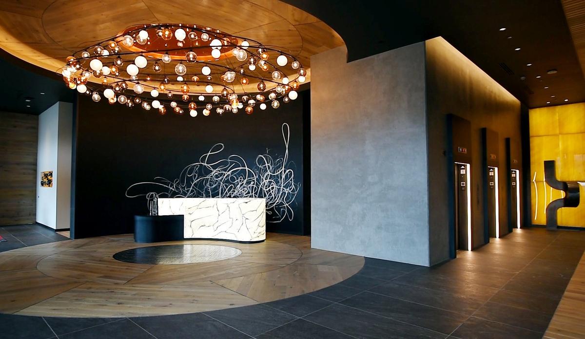 Two Light's lobby is illuminated by a chandelier made of glowing glass bulbs. The style of the building was inspired by the creative, industrial and slightly rustic vibe of the Crossroads Arts District.