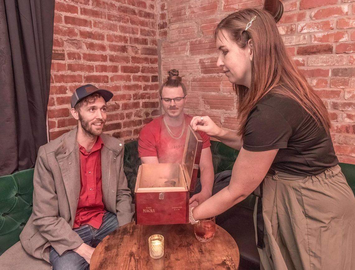 Jessica Stockton served drinks from the Smoking Box to Bobby Burk, left, and Ryan Newhouse.