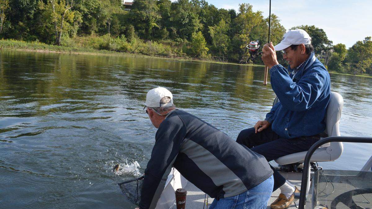 Fishers capture a rainbow trout in an Ozark lake. Branson’s lakes and mountains helped secure its place on Travel + Leisure’s 2024 list of best small towns.