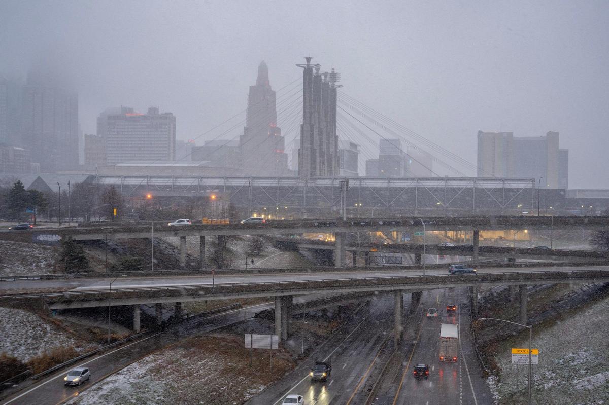 Snow falls in downtown Kansas City as commuters drive along the downtown loop on Monday, Jan. 8, 2024.