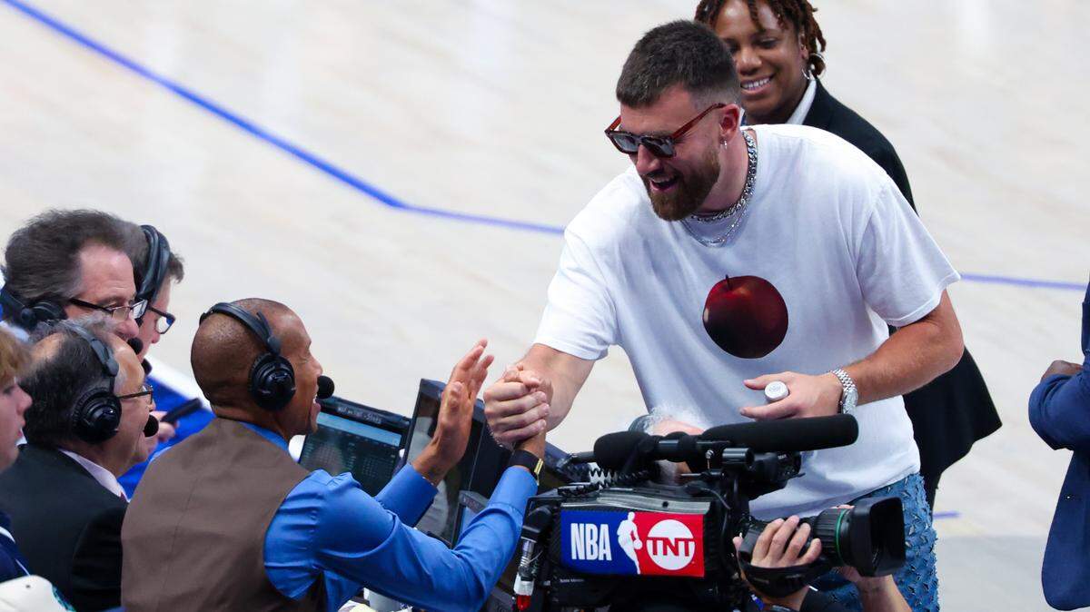 Kansas City Chiefs tight end Travis Kelce shakes hands with TNT announcer Reggie Miller during game three of the western conference finals for the 2024 NBA playoffs at the American Airlines Center.