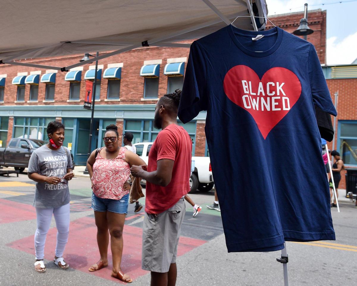 Jeff Harris with Heart Black Lives, right, talks with customers during Kansas City’s Juneteenth Heritage Festival in the 18th and Vine Jazz District Saturday, June 19, 2021.
