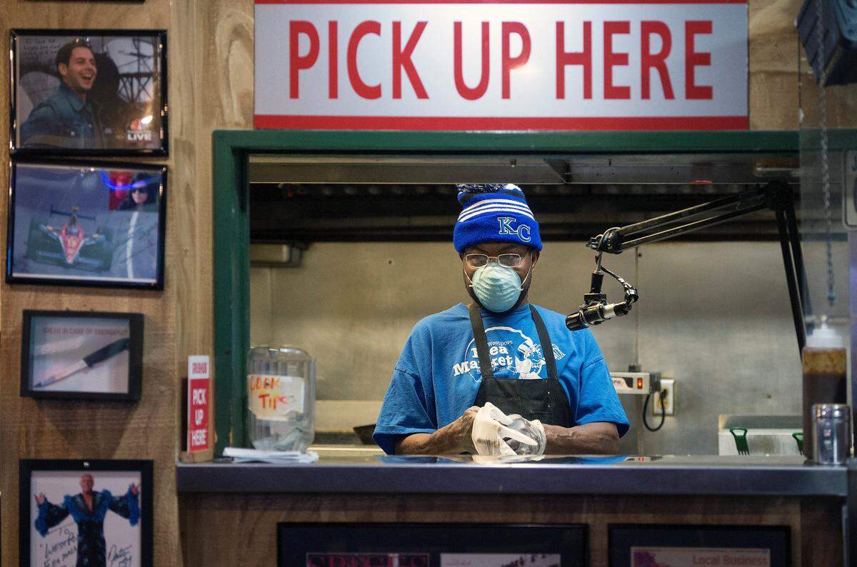 Jesse Smith dons a new pair of gloves before cooking up burgers for to-go orders at the Westport Flea Market. Kansas City restaurants are limited to carryout orders until Friday, but restaurants in Johnson County and the rest of Jackson County can begin limited dine-in service Monday.