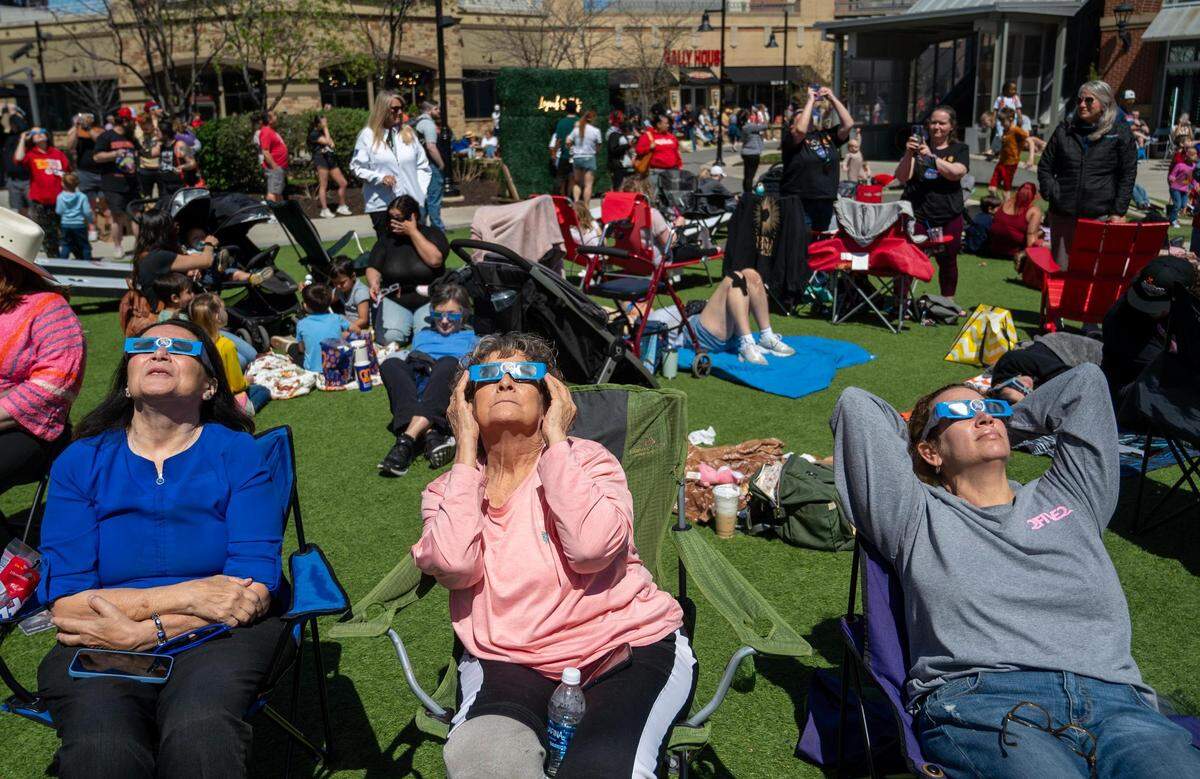 Sherry Clayton of Lawrence, from left, and Kathy Alexander and her daughter, Mikki Sander of Olathe, viewed the solar eclipse together on Monday.