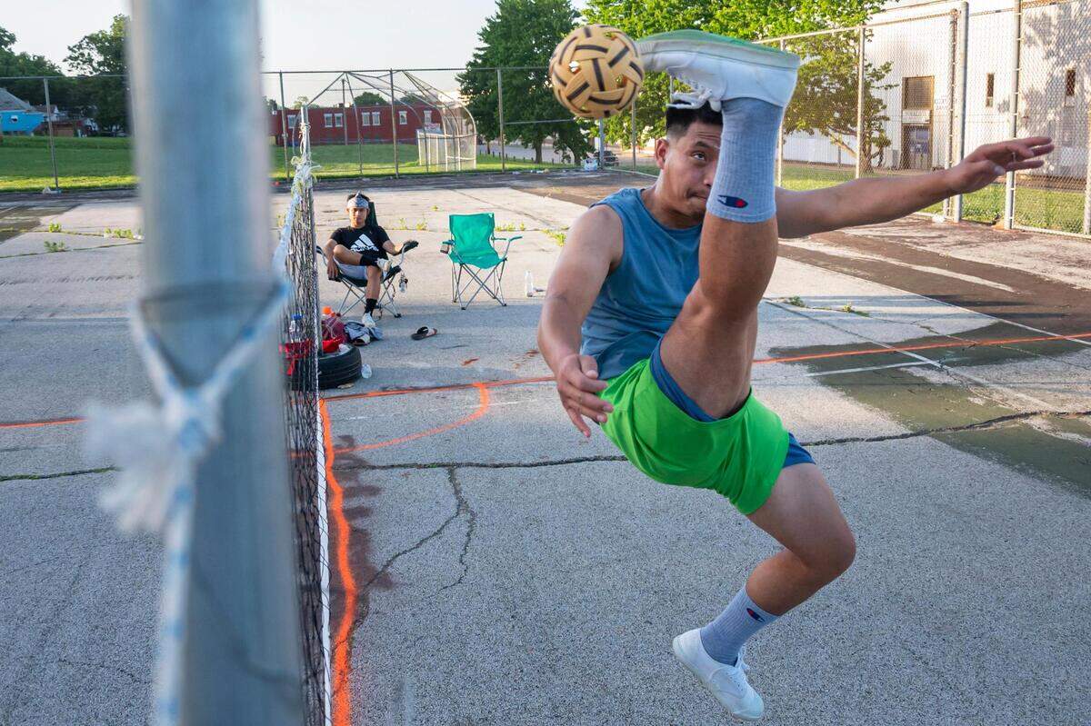 Day Lo kicks the ball as he and his friends play chinlone late in the afternoon at Sheffield Park in Kansas City on June 13, 2022.