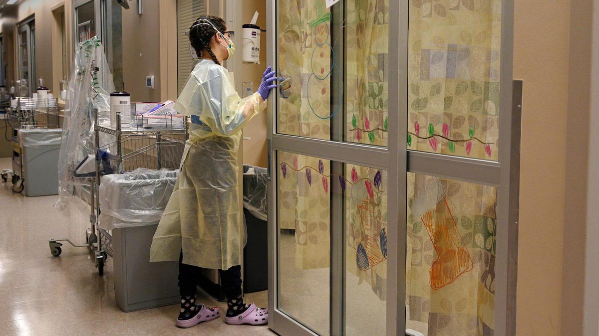 Delaney Swanson, a registered nurse in the COVID intensive care unit at University Health, enters a patient’s room for a visit Friday, Jan. 14, 2022. Patients’ rooms still displayed holiday decorations.
