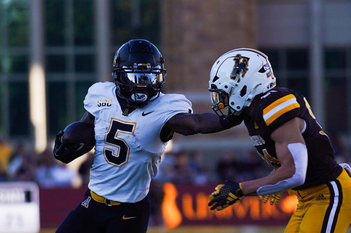 Then with the Appalachian State Mountaineers, running back Nate Noel stiff-arms a Wyoming Cowboys player during a game last season.