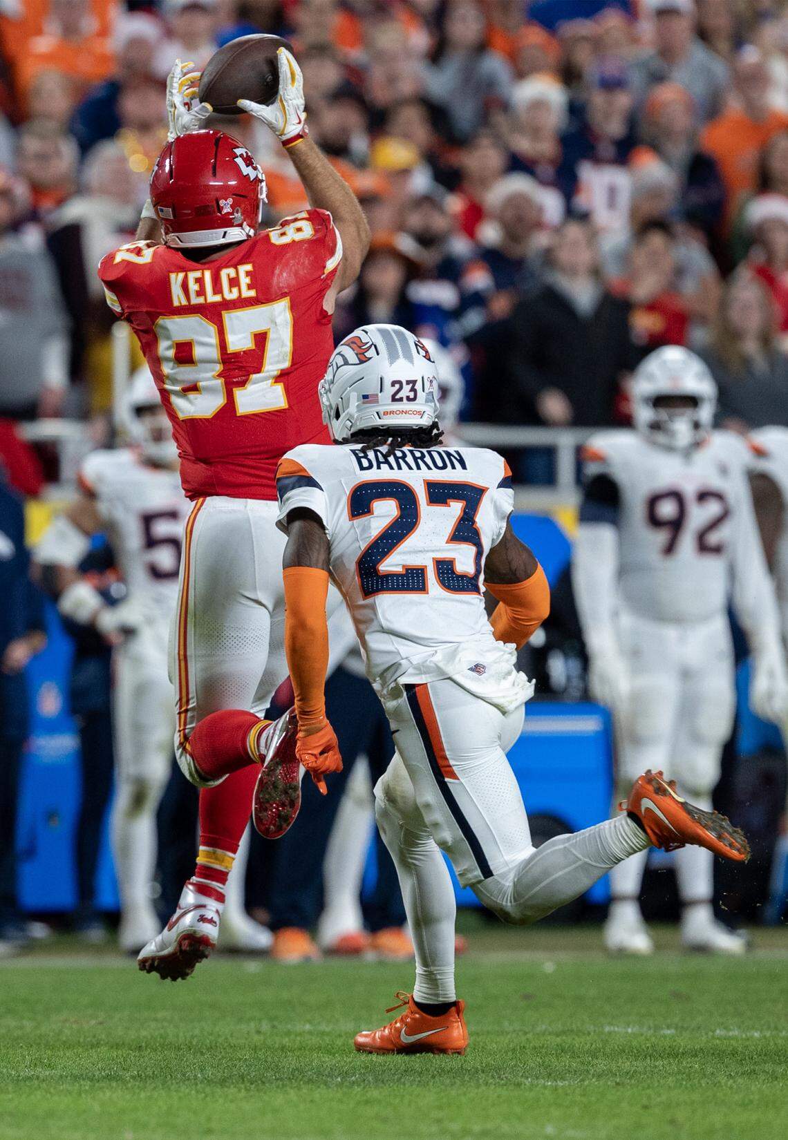 Kansas City Chiefs tight end Travis Kelce (87) catches a pass ahead of Denver Broncos cornerback Jahdae Barron (23) during the second half of the game at GEHA Field at Arrowhead Stadium on Thursday, Dec. 25, 2025, in Kansas City.  Denver defeated the Chiefs, 20-13. 