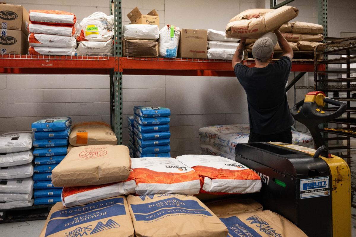 A worker lifts one of many 50 pound bags of flour to storage at Scratch KC. The North Kansas City facility produces about 40,000 pastries and sweets a day.
