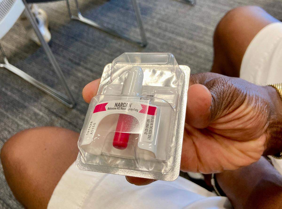 An audience member holds a sample of naloxone, which can help stop an opioid overdose.