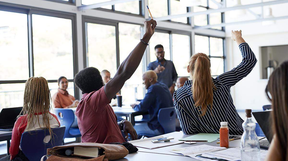 Students raising hands while sitting at desk in school classroom
Klaus Vedfelt