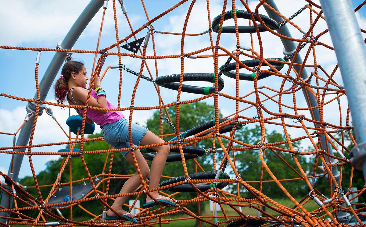 Daniella Uria, 12, of Olathe, climbs through a web of ropes at the new inclusive playground at Shawnee Mission Park. Her family wanted to check it out because her little brother has spina bifida.