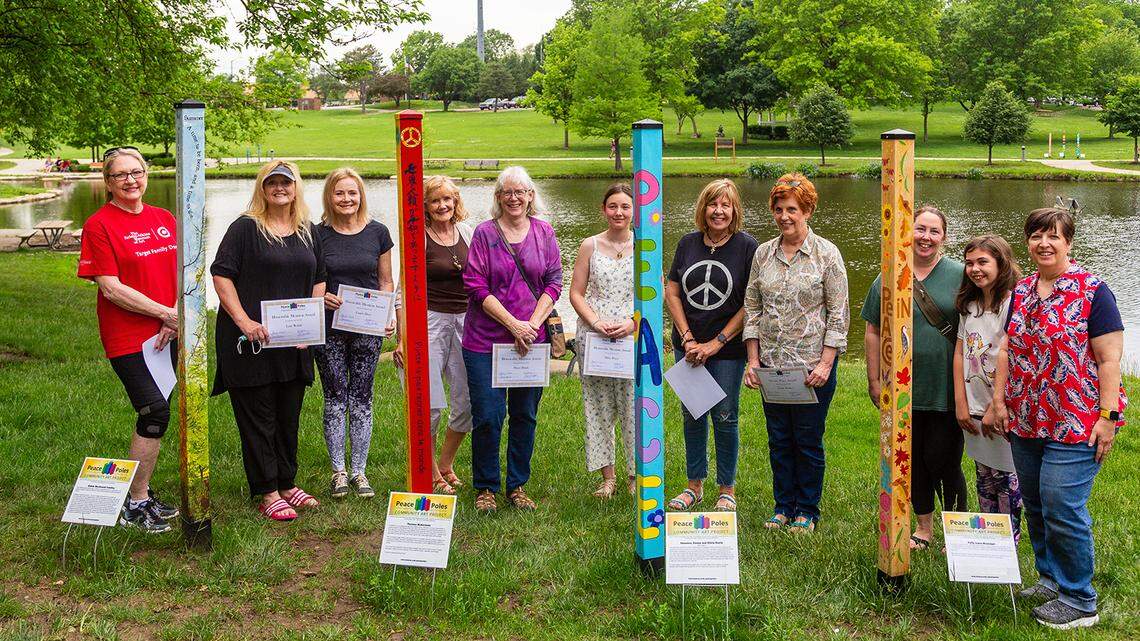 Designers/artists of these Peace Poles stand by their creations including (from left) Darlene Lindsey, Lory Rodak, Lori Hess, Jill Ragar, Marci Blank, Abbie Peters, Janet Hall, Cindy Heller, Kristin Archer and daughter Sarah Archer (representing Girl Scouts No. 1790), and Patty Jaksa Brundage. The poles will be on display at Sar-Ko-Par Park until Oct. 31 and then will be auctioned off Nov. 12, from 6-9 p.m. at the Lenexa City Hall.