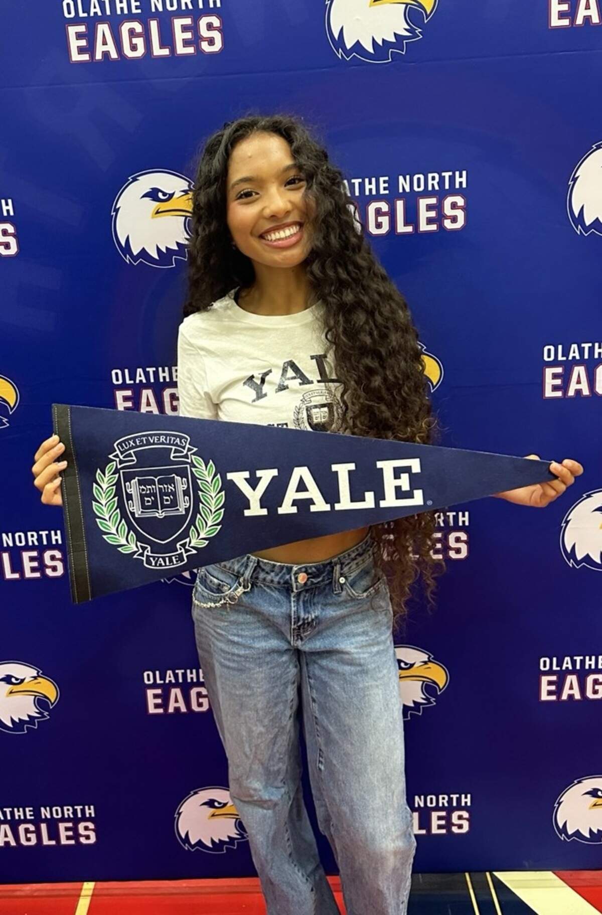 Avani Hocker Singh poses with a Yale pennant during her signing day ceremony inside the Olathe North gymnasium on April 17, 2026.