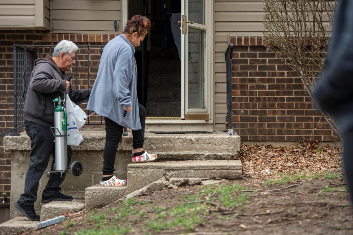 Joe Arce, left, helps his daughter Lisa Sidenstick up the steps of her home after she was released from North Kansas City Hospital on Wednesday. COVID-19 left Sidenstick unable to climb a flight of stairs without running out of breath.