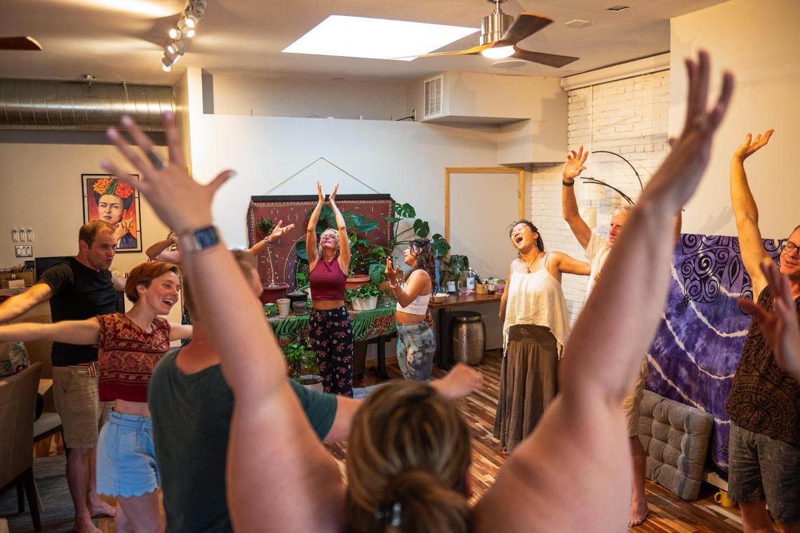 Laugher yoga students stretch and laugh together at Cafe Gratitude on Monday in Kansas City. “The purest human is the child, the baby,” Kalima said. “So when we get in contact with that aspect, it reminds us what it felt like to be trusting and to be joyful hearted.”