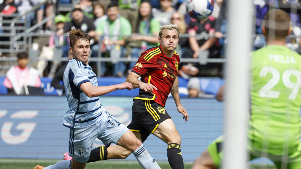 Seattle Sounders FC forward Jordan Morris (right) watches his shot against Sporting Kansas City go over the net at Lumen Field, while KC midfielder Jake Davis (left) follows the play on May 7, 2023.