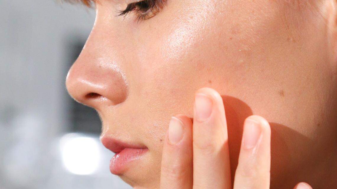 A woman applies skincare.