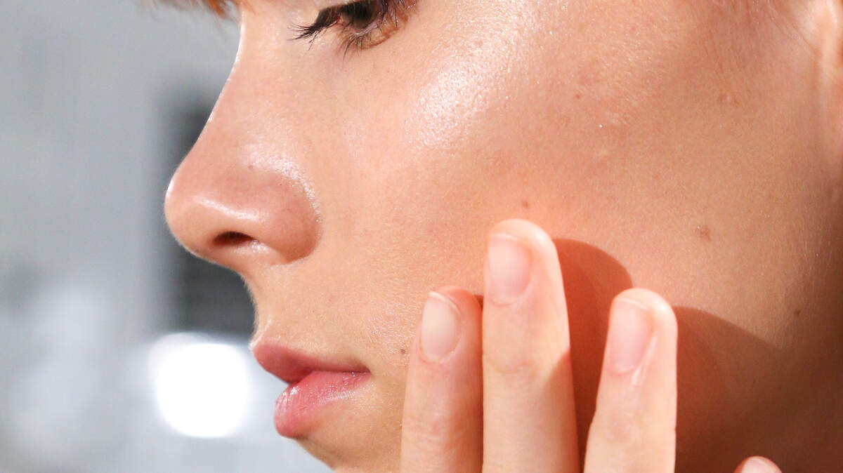A woman applies skincare.
