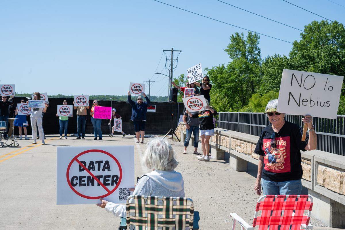 A group of protesters on Bly Road hold signs near the construction site for Nebius, a future AI data center being built in Independence, on Tuesday, May 12, 2026.