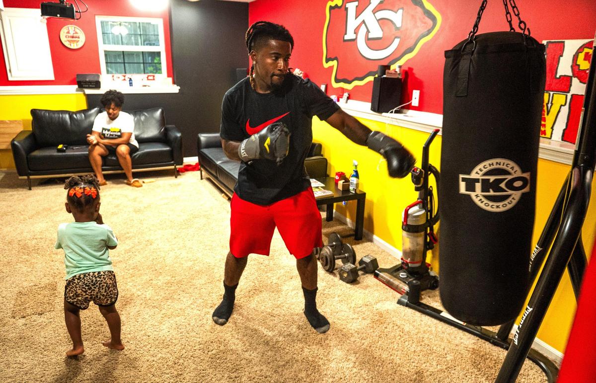 A heavy bag endures punches from John Roddy while his wife Mika and their daughter Esrael play nearby in their Blue Springs home.