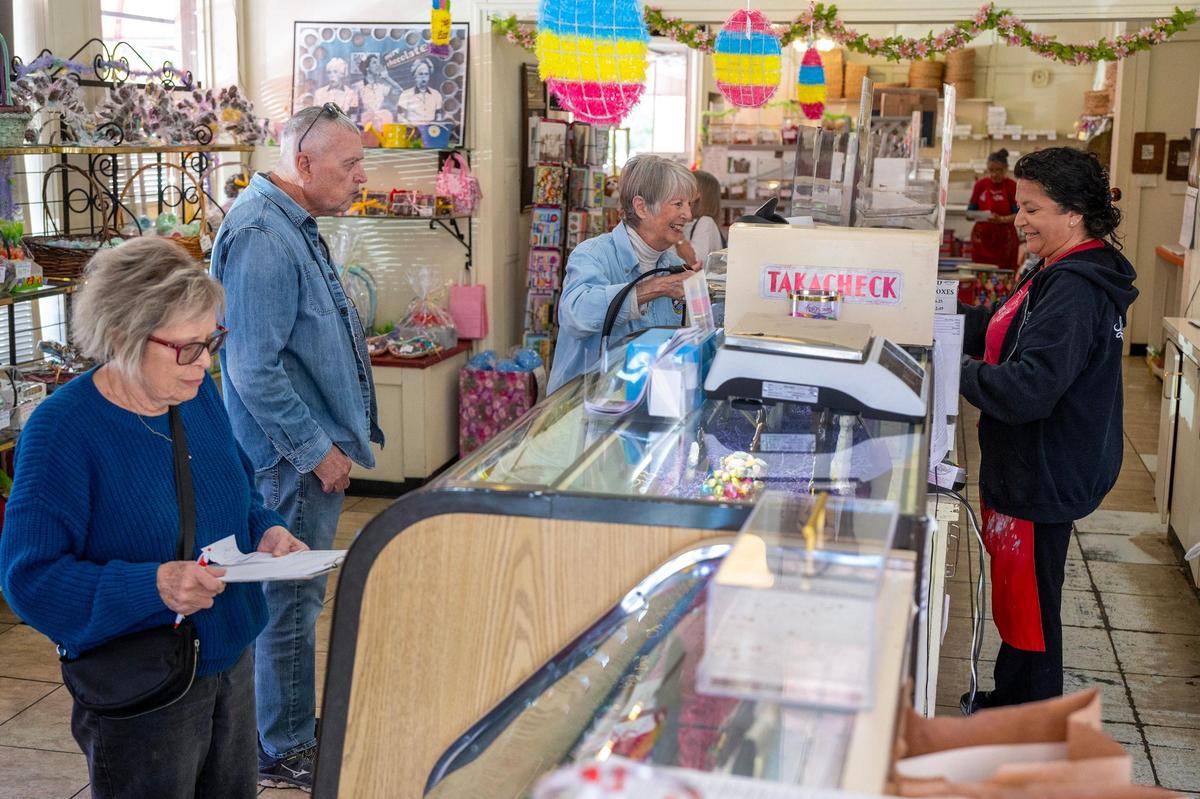 Christine Capra, right, a manager at Laura Little’s Candies, helps customers on Tuesday, April 15, 2025, in Prairie Village. Capra has worked at the shop for the past 40 years.