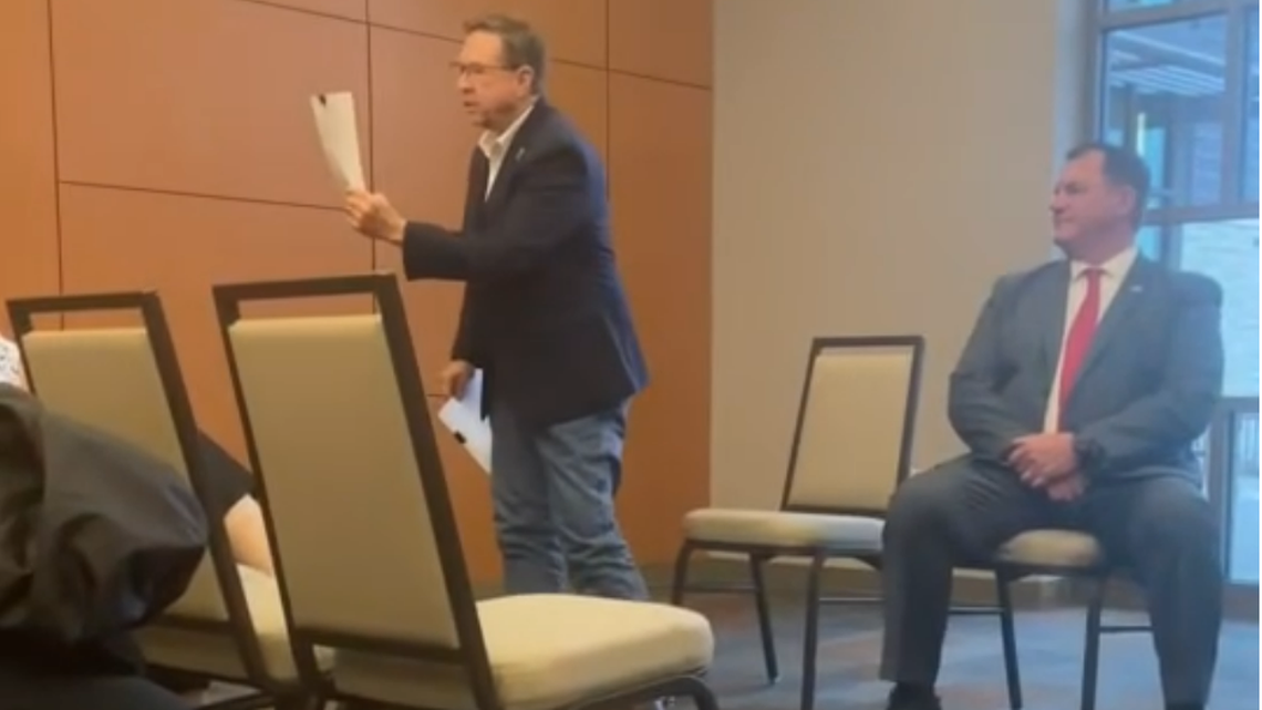Johnson County Sheriff Calvin Hayden, left, waves papers during a candidates’ forum in Olathe.