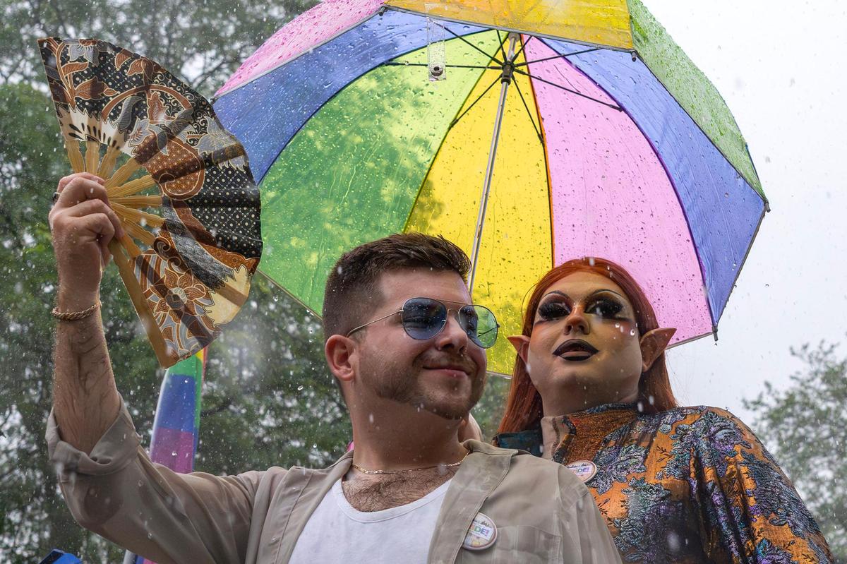 Parade participants smile as heavy rain falls during the KC Pride Parade along Mill Creek Parkway on Saturday in Kansas City.