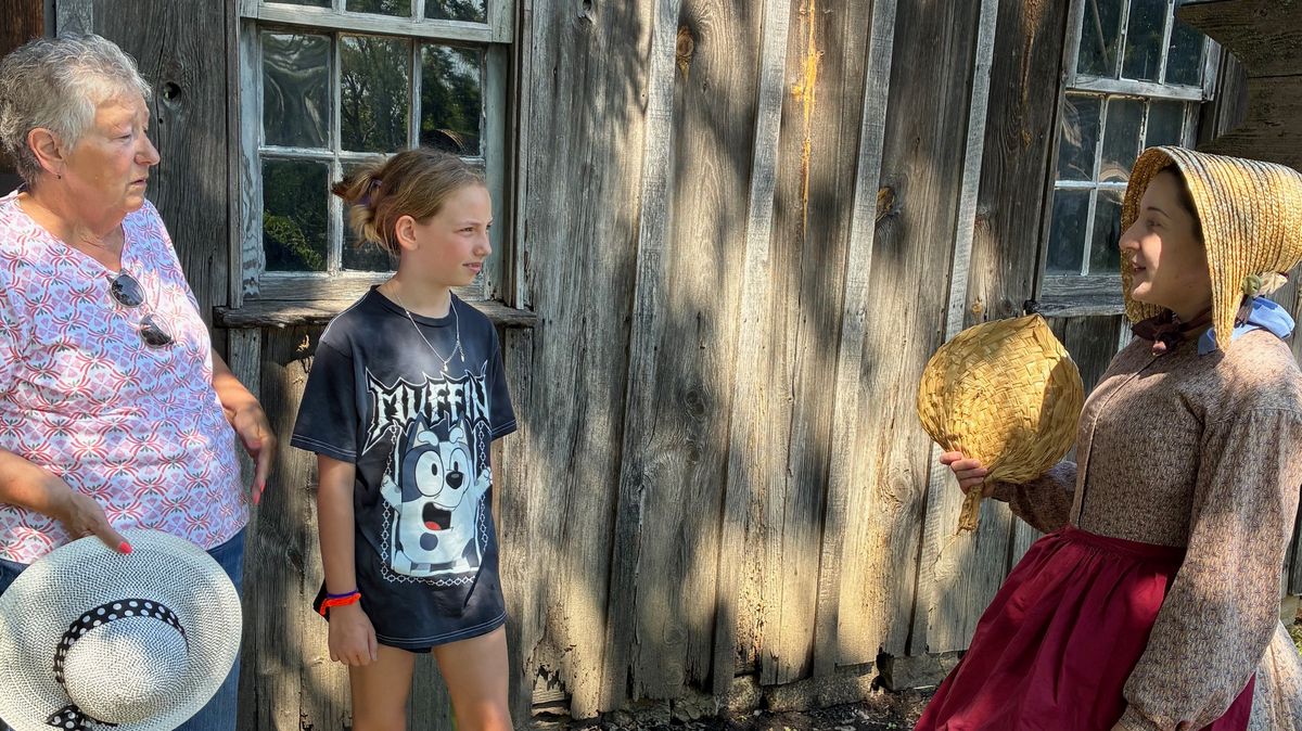 Simone Smith (far right), living history interpreter, speaks to visitors (from left) Lorna Robinett and Faye Robinett at the blacksmith.