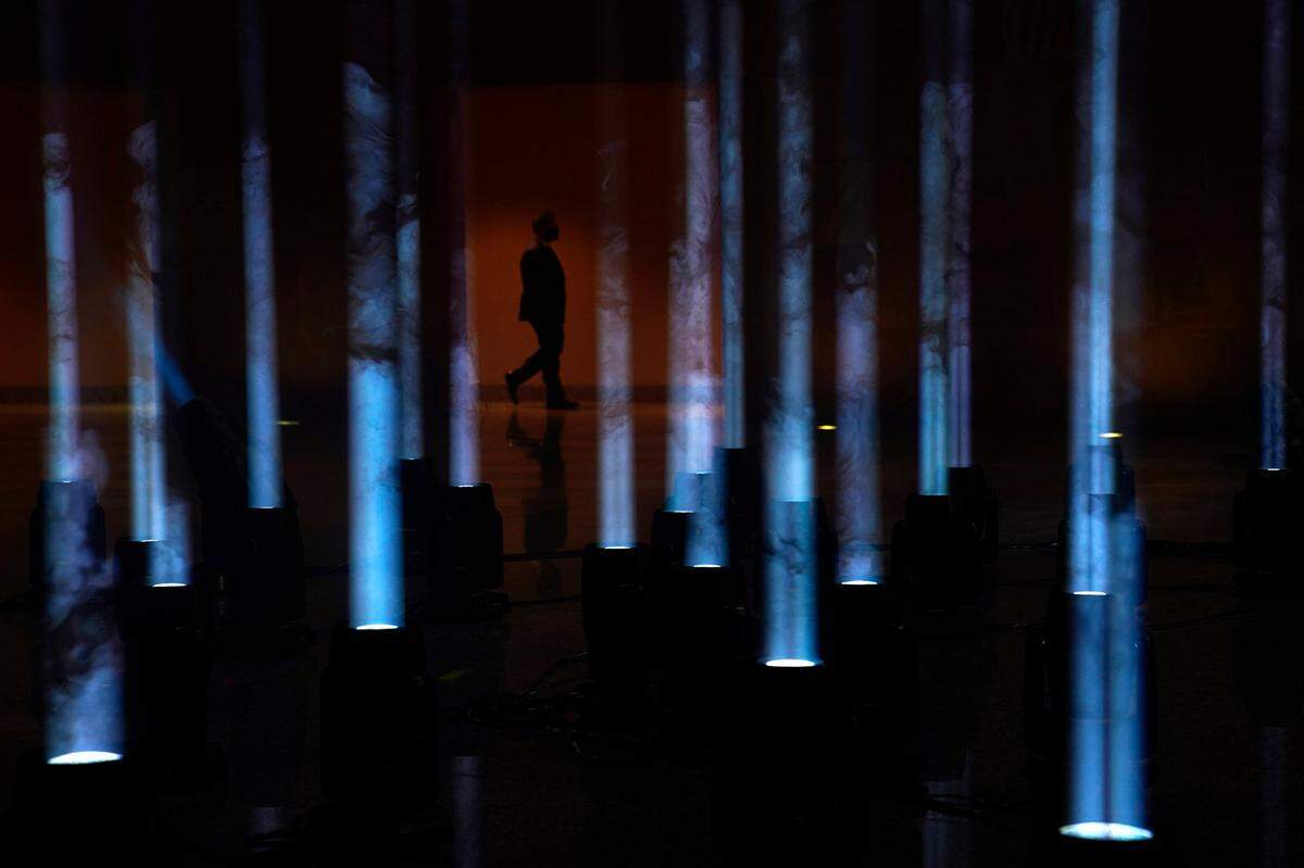 A person walks by shafts of light at the Clark County Government Center illuminated as part of a national memorial to lives lost to COVID-19, Tuesday, Jan. 19, 2021, in Las Vegas.