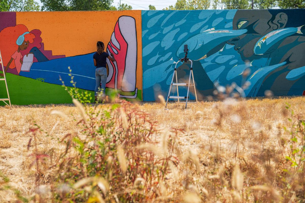 Jasmine Ali finishes painting her mural “Growth” on Friday, Sept. 15, 2023, at the Riverfront Heritage Trial in Kansas City. Ali’s mural is featured along side of fellow Kansas City based artists Emily Alvarez and her untitled mural inspired by the Missouri River.