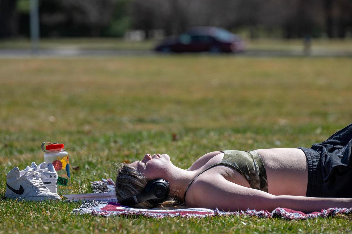 Charlotte Malone listens to music while sunbathing on the front lawn of The Nelson-Atkins Museum of Art on Tuesday in Kansas City.