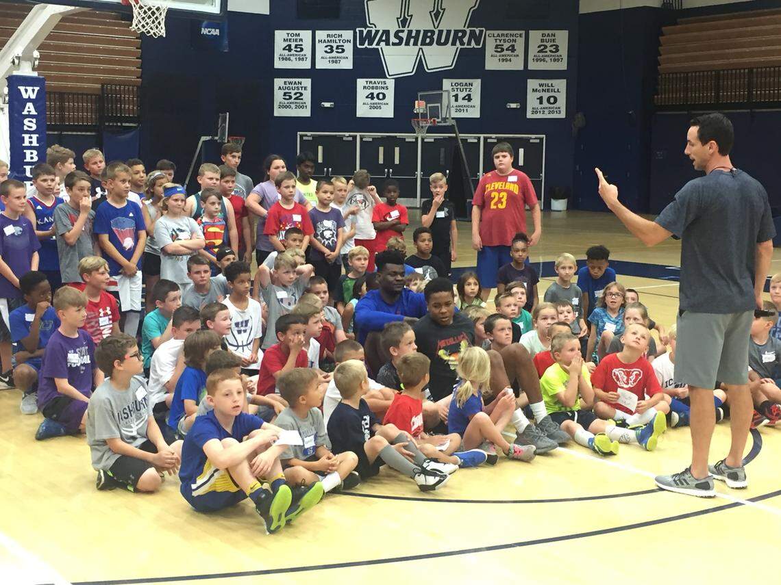 Kansas basketball players Udoka Azubuike (blue shirt, center) and Charlie Moore (black shirt, center) pose for a photo with children for a group photo at Washburn coach Brett Ballard's basketball camp on Monday morning at Lee Arena in Topeka.