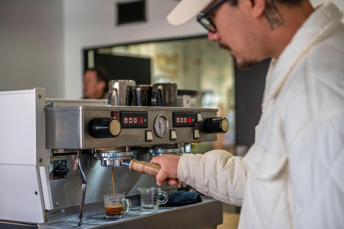 Josh Bella, owner of The Slow Bar, tests an espresso shot before opening in the Crossroads on Friday.
