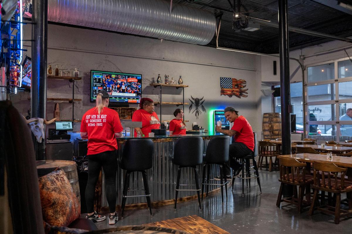 Employees of Savage Saloon chat around the bar as they wait for customers to arrive.